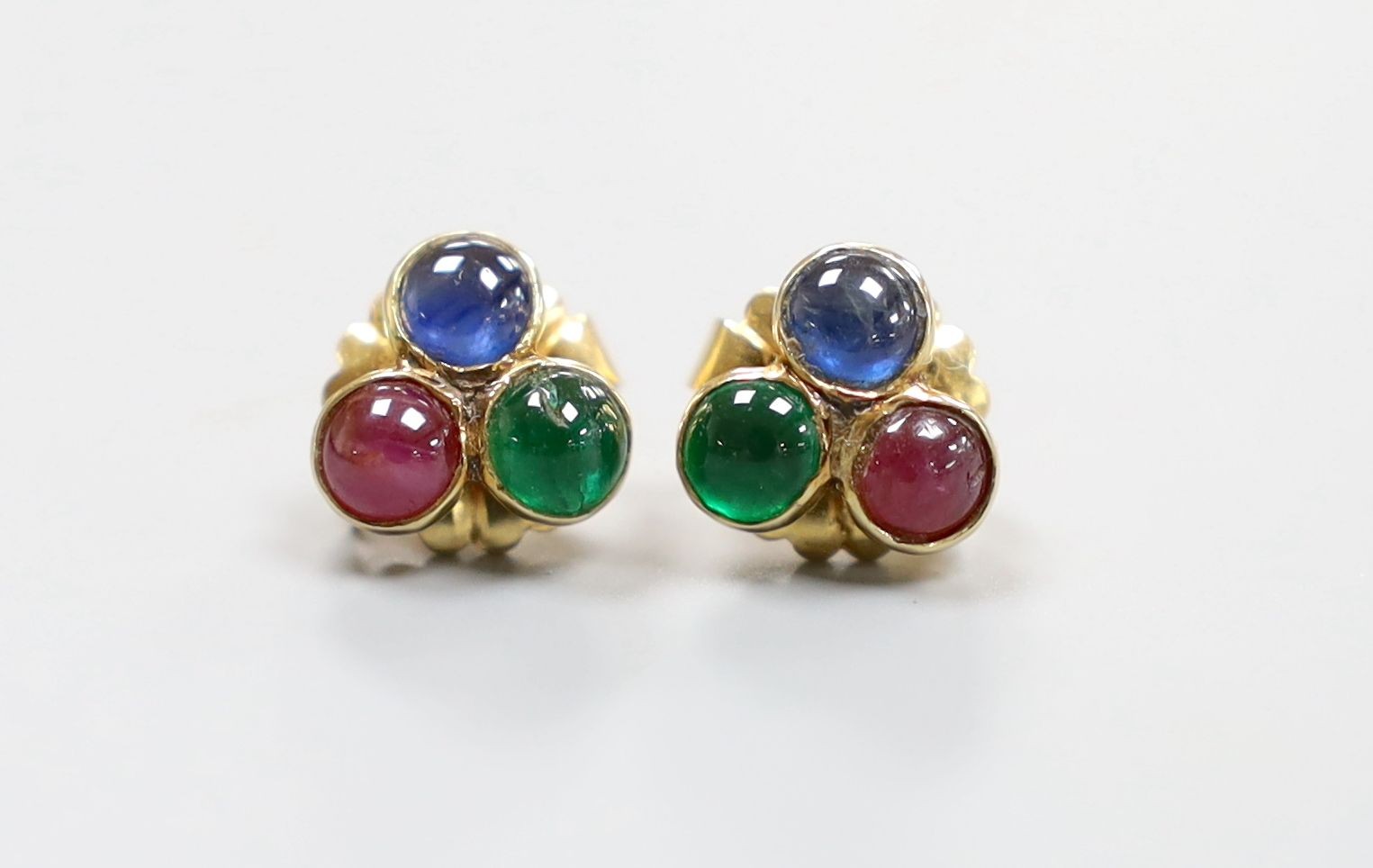 A modern pair of 750 and cabochon ruby, sapphire and emerald set three stone ear studs, 10mm, gross 3 grams.